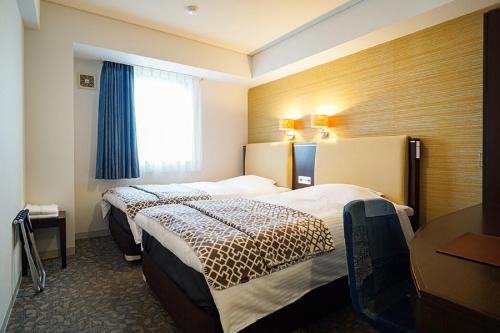 a hotel room with two beds and a window at Hotel BRS Hakodate Goryokaku Tower Mae in Hakodate