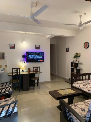 - un salon avec une table, des chaises et une télévision dans l'établissement Raga Homestay 2BHK- A homely guesthouse experience, à Guwahati