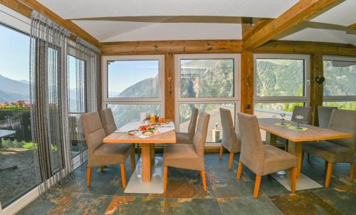a dining room with a table and chairs and windows at Pension Sonnleitner in Heiligenblut