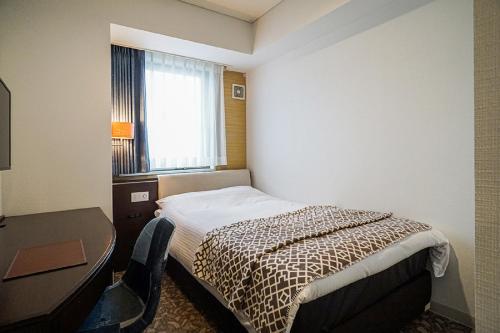 een hotelkamer met een bed, een bureau en een raam bij Hotel BRS Hakodate Goryokaku Tower Mae in Hakodate