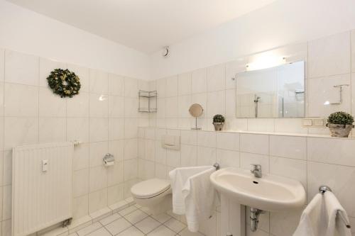 ein weißes Bad mit einem WC und einem Waschbecken in der Unterkunft Kurpark-Residenz 206 in Döse