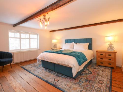 a bedroom with a bed and a chair and a window at Well Cottage in Grimston