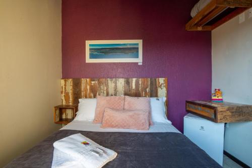 a bedroom with a bed and a purple wall at Pousada Flor de Lotus in Praia do Rosa