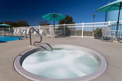 a hot tub in a patio with chairs and umbrellas at Days Inn by Wyndham Mountain Home in Mountain Home