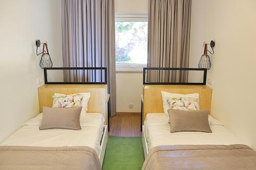 twee bedden in een kamer met een raam bij Casas de Alpedrinha in Alpedrinha