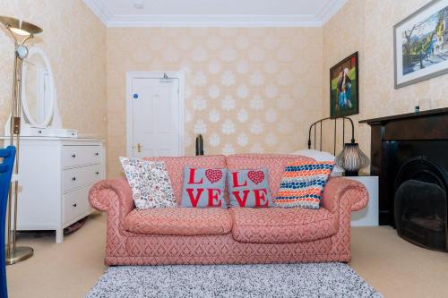 a living room with a pink couch with pillows on it at Spacious 4 Bedroom Apartment Near The MeadowsOld Town in Edinburgh