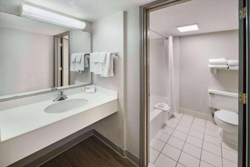 a bathroom with a sink and a toilet and a mirror at Days Inn by Wyndham Del Rio in Del Rio