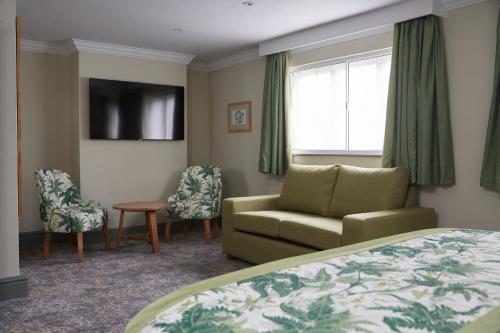 a hotel room with a bed and a couch and a chair at Governors House by Greene King Inns in Cheadle Hulme