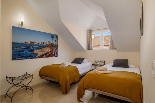 two beds in a room with a painting on the wall at Luxury Penhouse, Sotogrande Marina - Located in an exclusive island of the Marina in Sotogrande