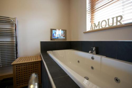 baño con bañera y TV en la pared en Wesdale, Stromness - 3 Bedroom Holiday Cottage en Orkney