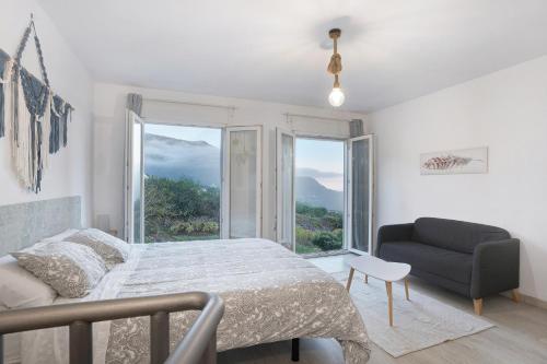 a bedroom with a bed and a couch and a window at Casita Rural La Piñera in Los Realejos