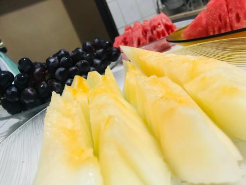 a plate with slices of fruit on a table with grapes at Hotel Gasometro in São Paulo