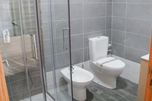 a bathroom with a toilet and a glass shower at São Pedro Country House in Campo Maior