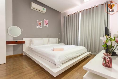 een slaapkamer met een wit bed en een bureau bij Sunrise City in Ho Chi Minh-stad