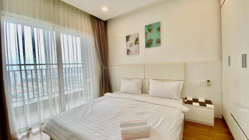 ein Schlafzimmer mit einem weißen Bett und einem großen Fenster in der Unterkunft Sunrise City 3 Bed Room in Ho-Chi-Minh-Stadt