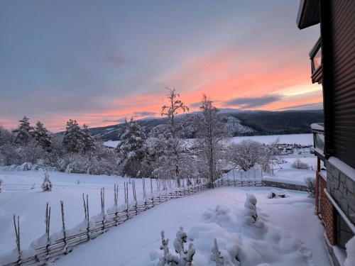 a snow covered yard with a fence and a sunset at Åre Travel - Tottbacken in Åre