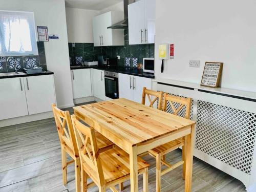 cocina con mesa de madera y sillas en Fabulous, Spacious, Newly Refurbished Home close to Heathrow Airport en Hayes