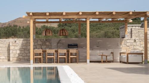 un pabellón con mesa y sillas junto a una piscina en Ayali Villa II, a divine luxury homestay, By ThinkVilla, en Achlades