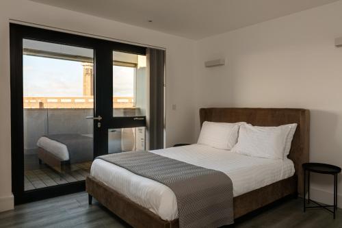 a bedroom with a bed and a balcony with a view at Charles Hope London Brentford in Brentford