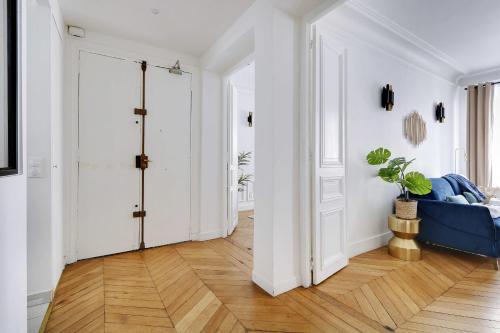 un couloir avec des murs blancs et un canapé bleu dans l'établissement Classy appartment - Arc de Triomphe, à Paris