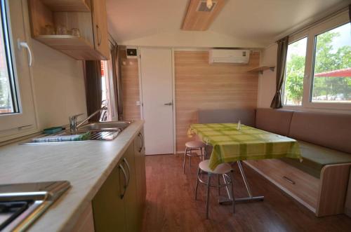a kitchen with a table with a green table cloth on it at Campsite Pisak - mobile homes by the sea in Seline