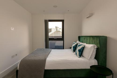 a bed with a green headboard in a bedroom at Charles Hope London Brentford in Brentford