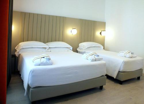 2 letti in camera d'albergo con lenzuola e cuscini bianchi di BB Hotels Smarthotel Derose a Firenze