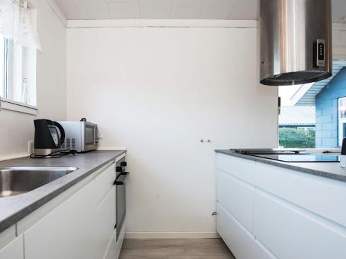 ヒュールスミンネにある6 person holiday home in Juelsmindeのキッチン(白いキャビネット、カウンタートップ付)