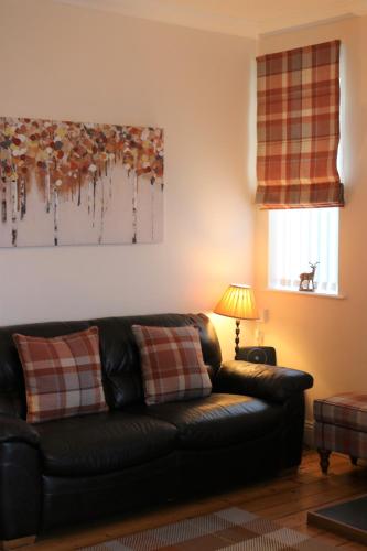 a living room with a black leather couch and a lamp at Cheviot View - Newton by the Sea, Northumberland in Alnwick