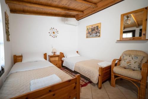 a bedroom with two beds and a chair and a mirror at Kalimera Villa, Afissos Pelion in Afissos