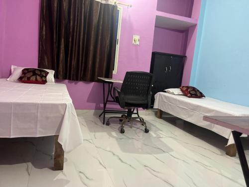 a room with two beds and a desk and a chair at Riru girlstay in Patna