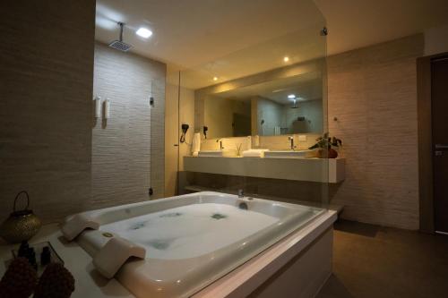 a bath tub in a bathroom with a large mirror at Hotel Cabo Branco Atlântico in João Pessoa