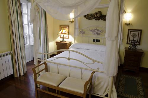 a bedroom with a white canopy bed and a chair at Posada Casa de don Guzman in Vega de Pas