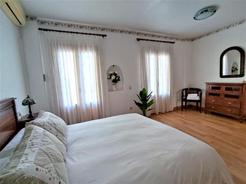 a bedroom with a large white bed and a dresser at Casa Suni Alicante Centro in Alicante