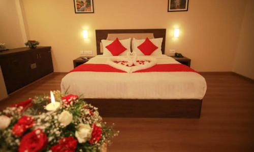 um quarto com uma cama grande com almofadas vermelhas e flores em Hotel kadambari em Kāladi