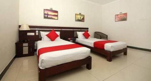 a bedroom with two beds with red and white sheets at Hotel kadambari in Kāladi