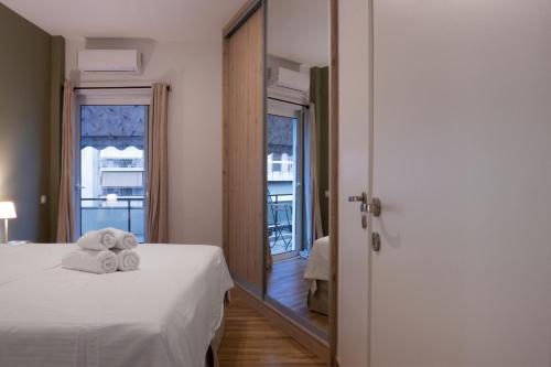 1 dormitorio con 1 cama con toallas y espejo en Colorful, Bright, Spacious, 2BR APT in Vyronas en Athens