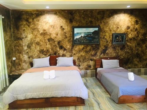 a bedroom with two beds and a stone wall at xaythone guest house in Savannakhet