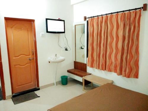 baño con lavabo y TV en la pared en Hotel Sai Darshan, en Shirdi