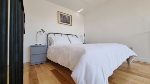 a white bedroom with a bed and a lamp at The Studio Room at Wester Den in Arbroath