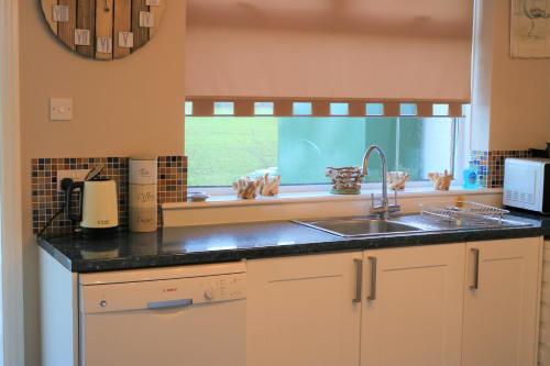 uma cozinha com um lavatório e uma janela em Cheviot View - Newton by the Sea, Northumberland em Alnwick