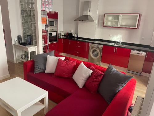 a living room with a red couch and a kitchen at ANARAL-Casco Viejo Gijon-AUTOCHECK 24h in Gijón
