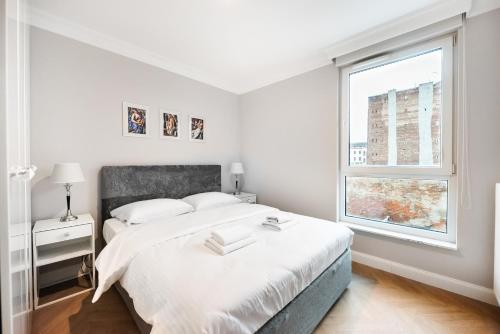 biała sypialnia z łóżkiem i oknem w obiekcie Stara Praga Superior Apartment w Warszawie