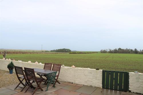 una mesa y sillas en un patio con vistas a un campo en Cheviot View - Newton by the Sea, Northumberland, en Alnwick