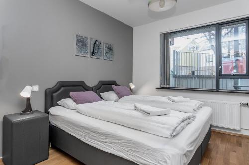 レイキャビクにあるSunny Apartment - By the Sea in City Centerのベッドルーム1室(白いシーツと紫色の枕が備わる大型ベッド1台付)