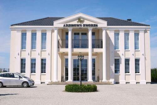 a white building with a car parked in front of it at Adzikowy Dworek in Wyszków