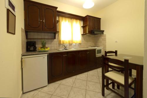 a kitchen with wooden cabinets and a table and a sink at Ideal House in Parga
