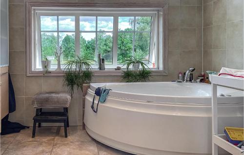 2 Bedroom Amazing Home In Havstenshult : حوض استحمام أبيض في حمام مع نافذة