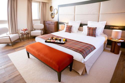 a hotel room with a large bed with a tray of food on it at Les Suites de la Potinière in Courchevel