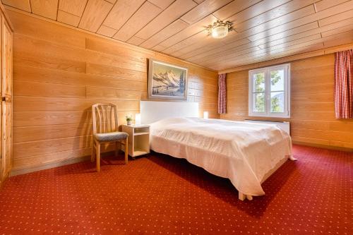 a bedroom with a bed and a chair and a window at Berghaus Tschengla by A-Appartments in Bürserberg
